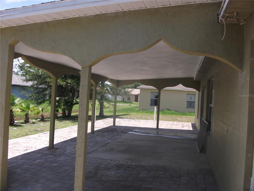 A covered patio with a concrete and paver floor features decorative arched support columns — 221 COBALT DRIVE, KISSIMMEE, FL