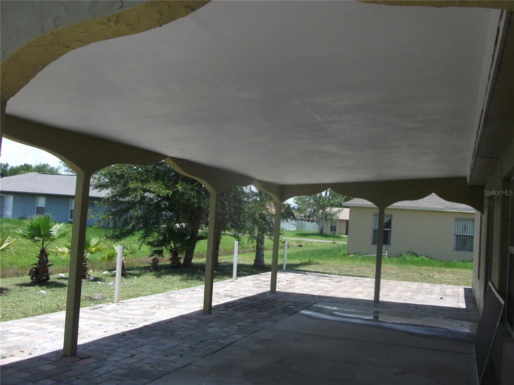 A covered patio features a paved floor, a white ceiling, and decorative arched support beams — 221 COBALT DRIVE, KISSIMMEE, FL