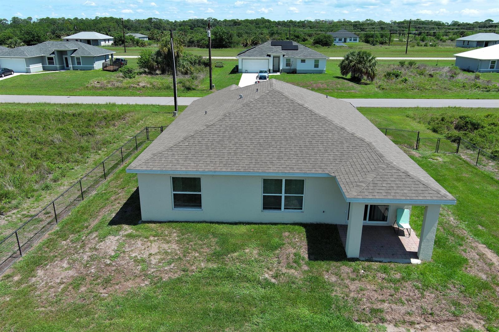 An aerial view of a single-story house with a gray shingled roof and fenced yard — 113 Plantation Drive, FL 33935, FL