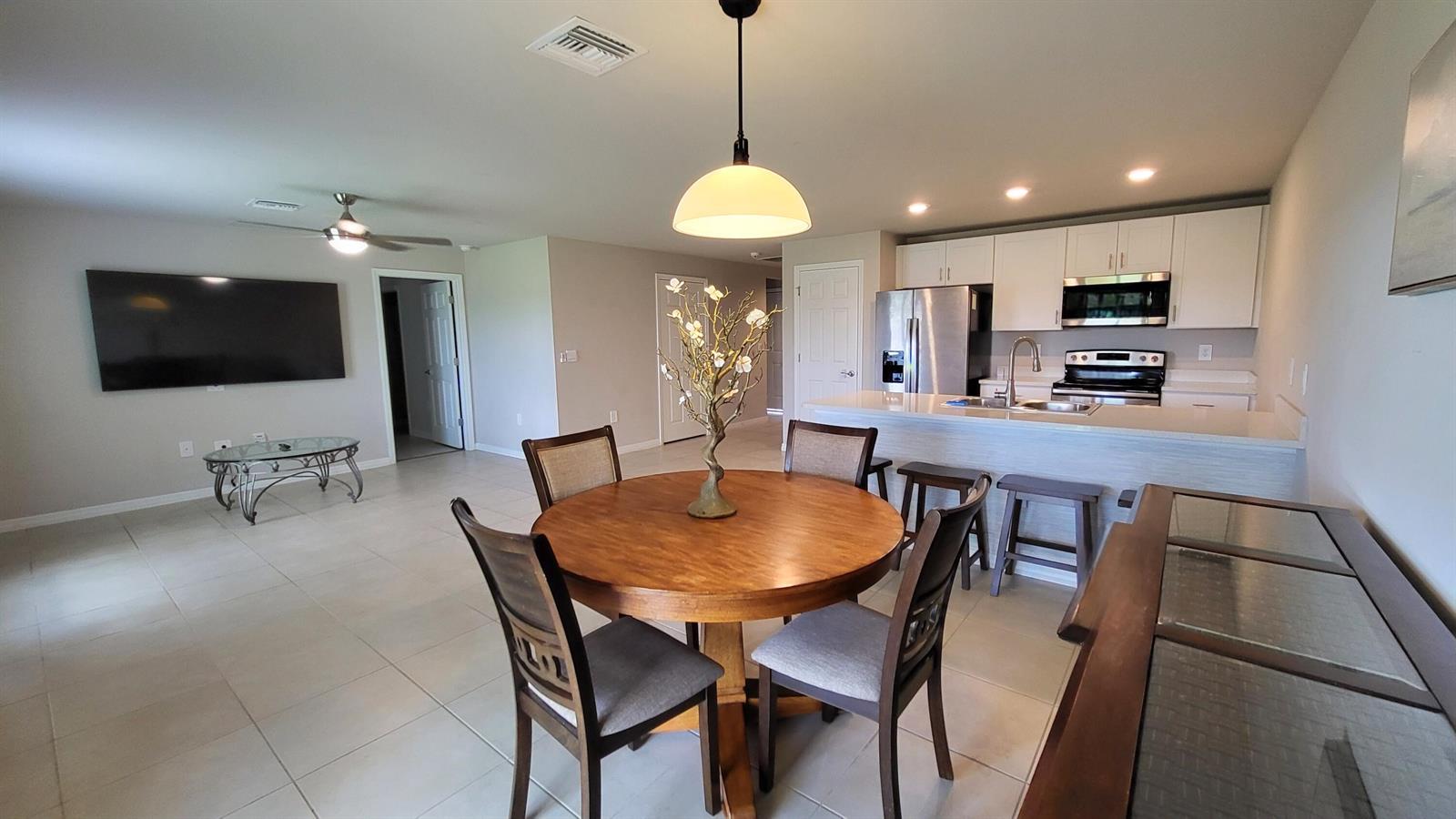 An open-concept kitchen and dining area features a round wooden table and white cabinetry — 113 Plantation Drive, FL 33935, FL
