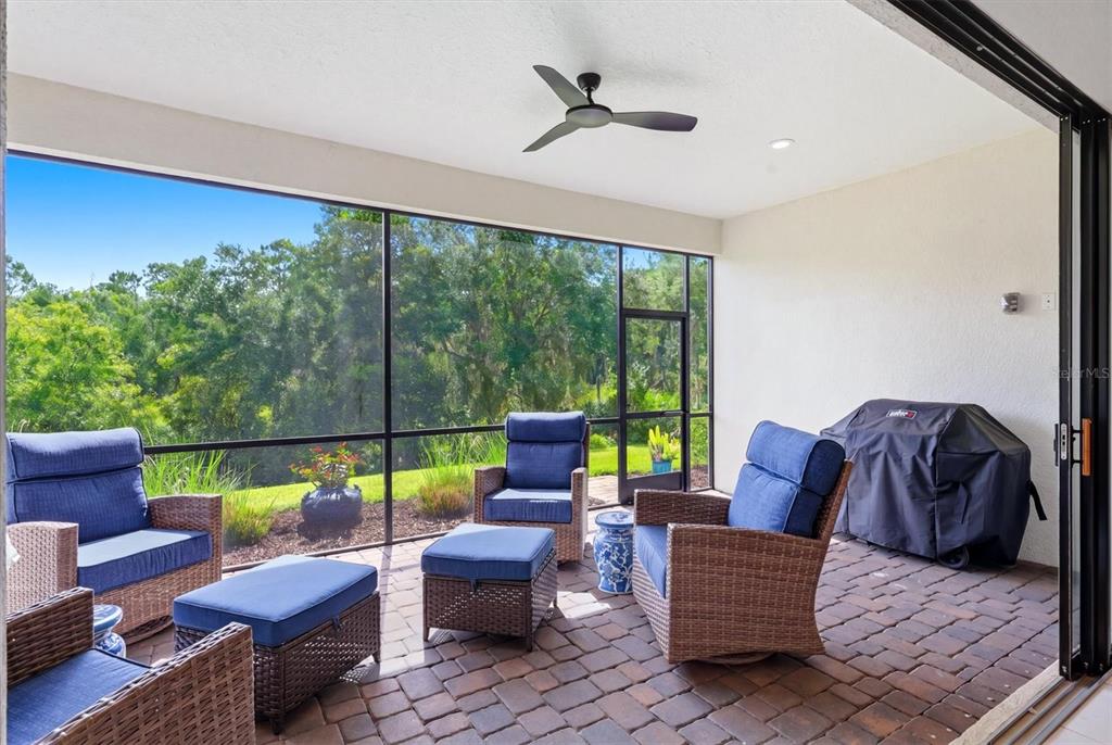 A screened-in patio with wicker furniture, a ceiling fan, and a view of trees — 13231 INDIGO WAY, BRADENTON, FL