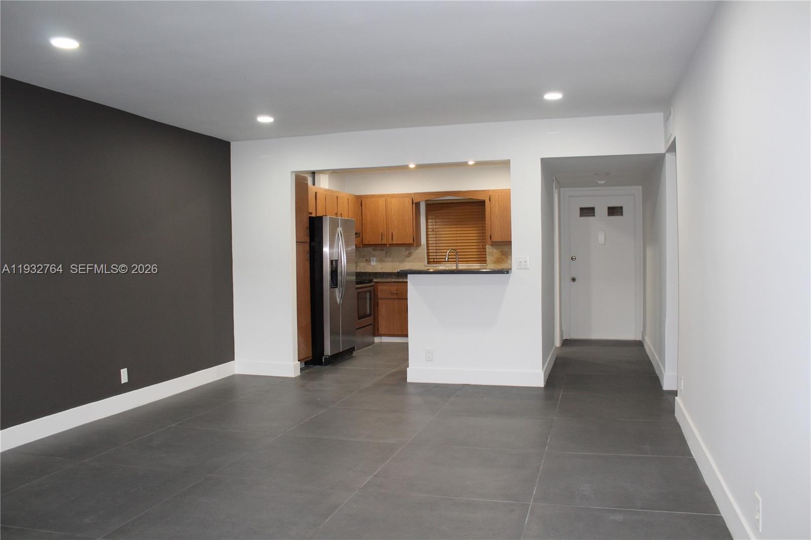 This room features large gray floor tiles, a dark accent wall, and an open kitchen — 5140 SW 40th Ave # 3C, Dania Beach FL 33314, DANIA BEACH, FL