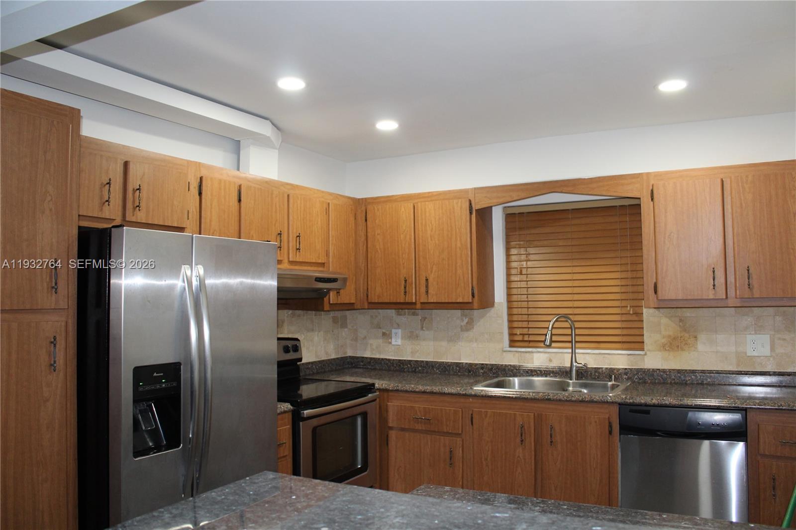A kitchen features wood cabinets, stainless steel appliances, and a dark granite countertop — 5140 SW 40th Ave # 3C, Dania Beach FL 33314, DANIA BEACH, FL