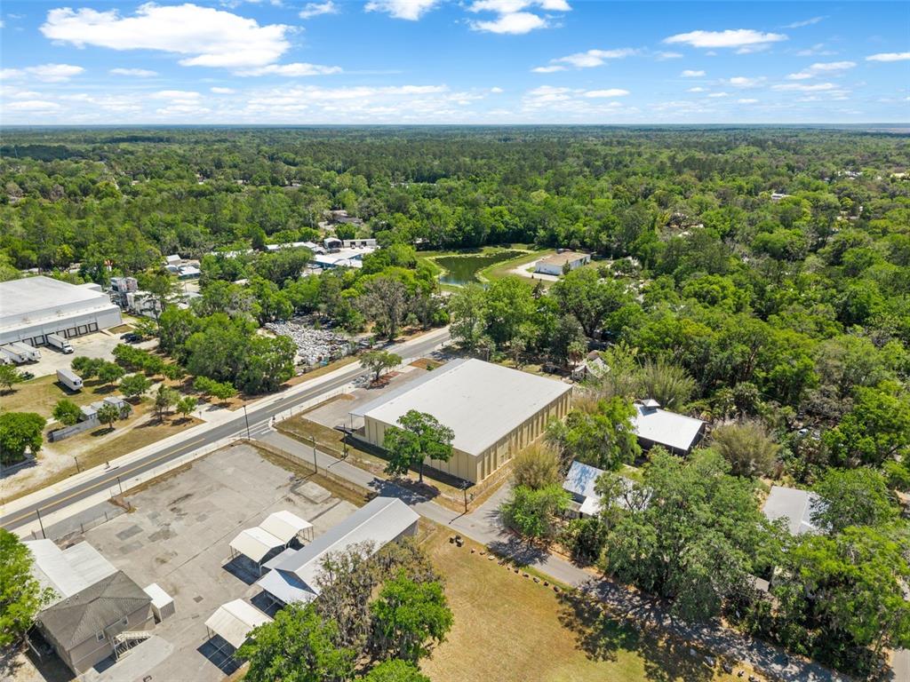 An aerial view shows a large warehouse building surrounded by trees, parking, and a road — 1030 SE 4TH STREET, GAINESVILLE, FL
