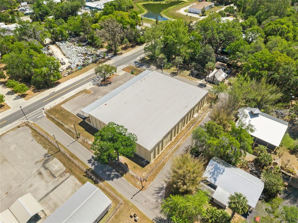 An aerial view shows a large warehouse building with a metal roof surrounded by trees — 1030 SE 4TH STREET, GAINESVILLE, FL
