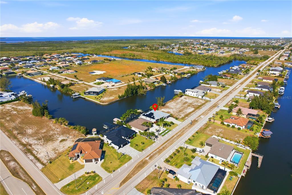 An aerial view shows a waterfront house with solar panels and a pool — 1616 N OLD BURNT STORE ROAD N, CAPE CORAL, FL