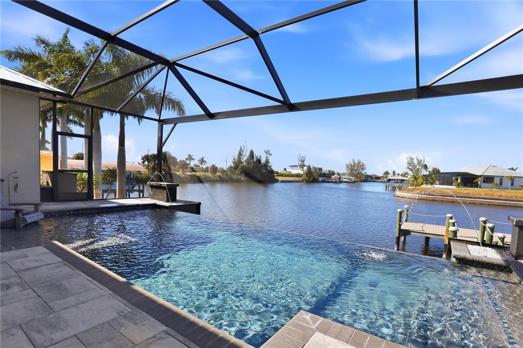 An infinity pool sits inside a screened lanai overlooking a canal with a private dock — 1616 N OLD BURNT STORE ROAD N, CAPE CORAL, FL