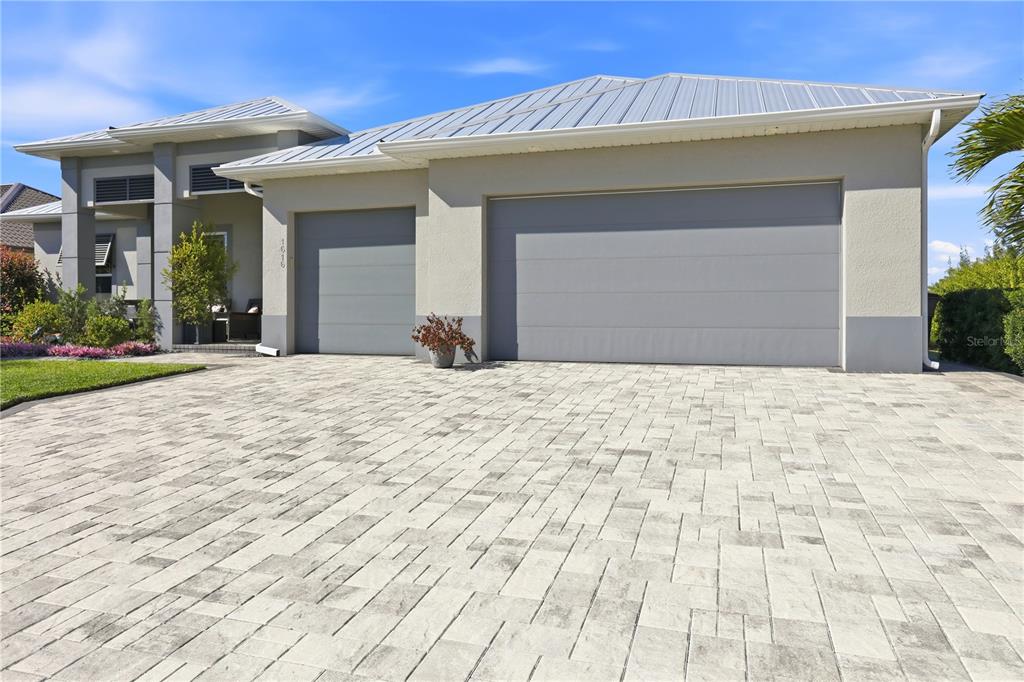 A modern house exterior features a paved driveway, a three-car garage, and a metal roof — 1616 N OLD BURNT STORE ROAD N, CAPE CORAL, FL