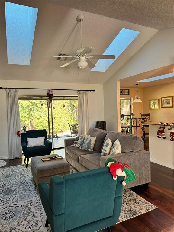 A living room features a grey sofa, teal armchairs, a ceiling fan, and two skylights — 4487 TRAILS DRIVE, SARASOTA, FL