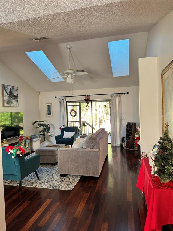 A living room features hardwood floors, a vaulted ceiling with skylights, and a ceiling fan — 4487 TRAILS DRIVE, SARASOTA, FL
