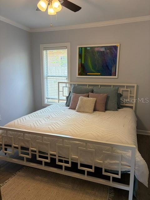 A bedroom features a white geometric metal bed frame, a textured quilt, and abstract wall art — 7211 N TALIAFERRO AVENUE, TAMPA, FL