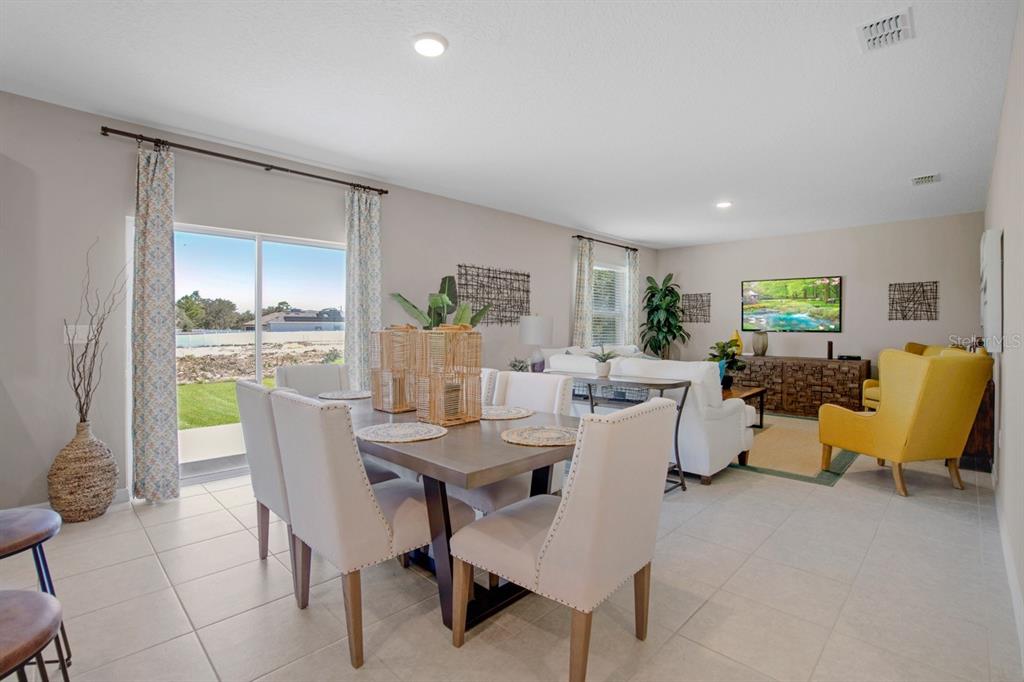 An open-concept dining and living area features tile flooring, neutral walls, and a sliding door — 314 BOWFIN LANE, POINCIANA, FL