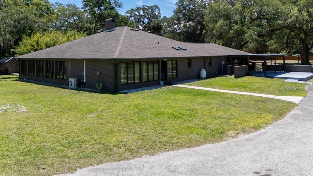 A low-slung, dark brick house with a hip roof sits on a grassy lot — 830 NW 111TH LANE, OXFORD, FL