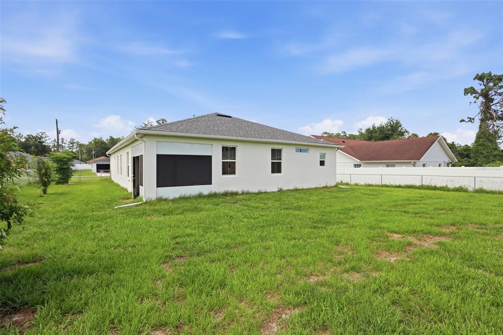 The exterior view shows the back of a white house with a screened-in porch area — 5574 SW 128TH PLACE, OCALA, FL
