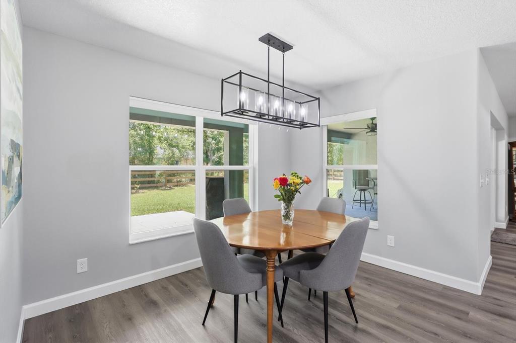 A dining area features a round wooden table, four gray chairs, and a rectangular pendant light — 232 E FALCON STREET, DUNNELLON, FL