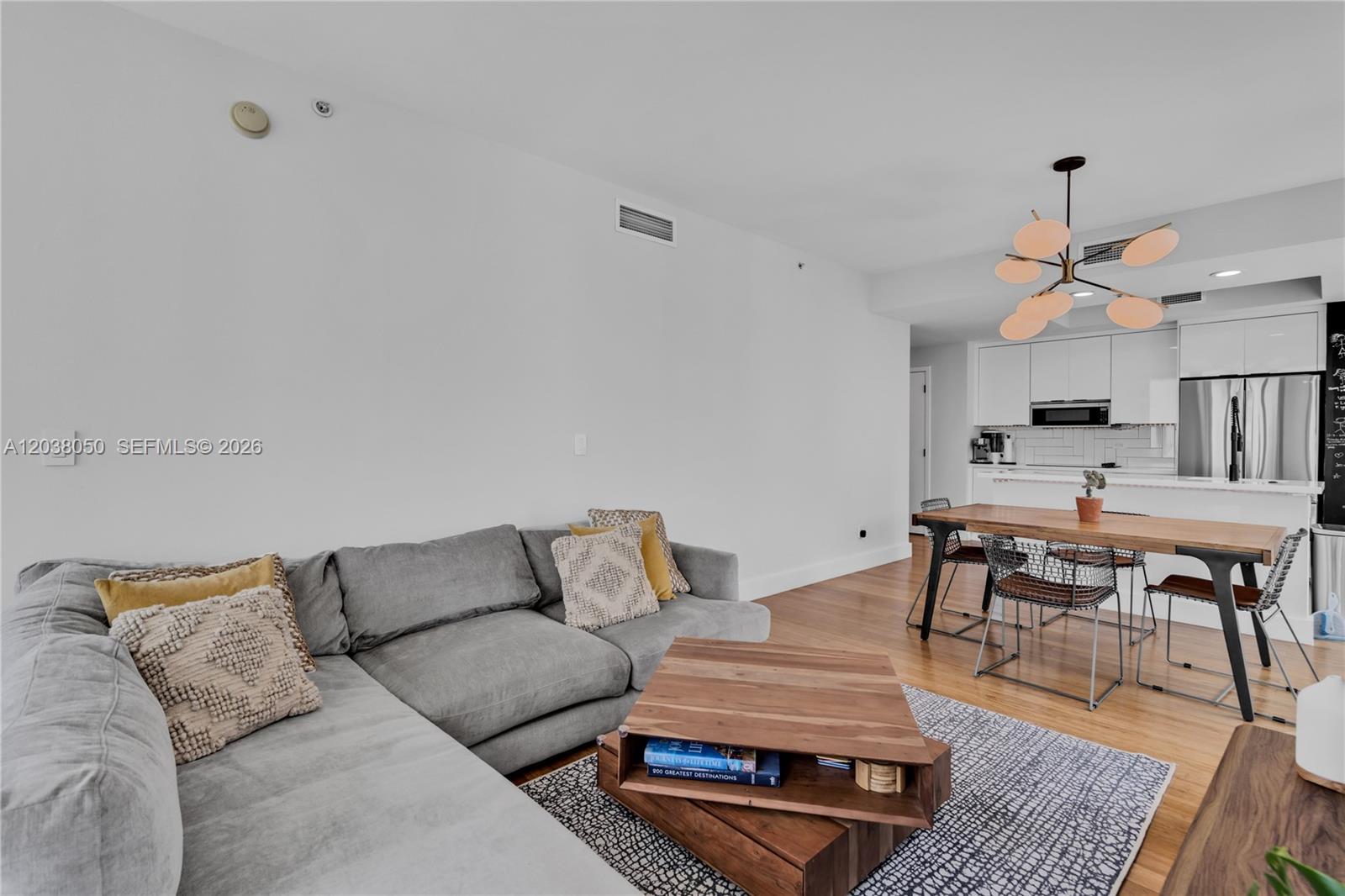 A living room with a grey sectional sofa, wooden coffee table, and adjacent dining area — 888 Biscayne Boulevard # 812, Miami FL 33132, MIAMI, FL