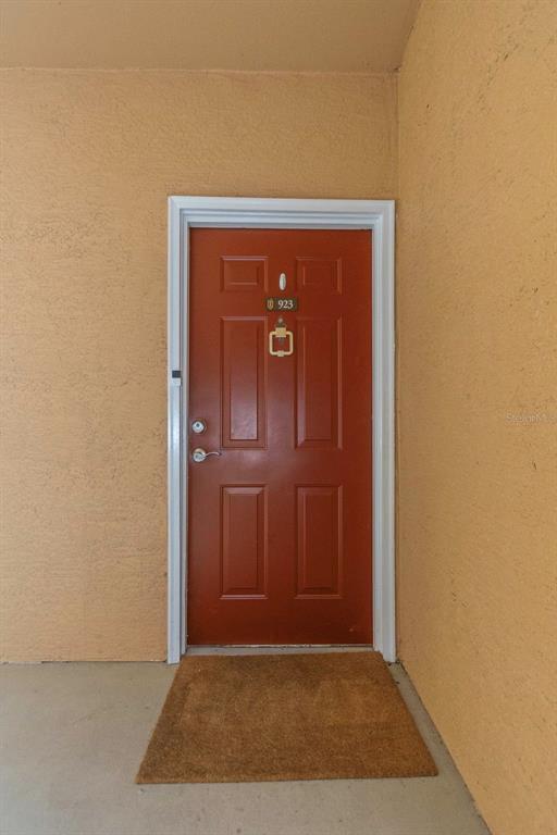 A red front door with a gold knocker and number 923 sits in a stucco entryway — 2199 CHIANTI PLACE UNIT 9-0923, PALM HARBOR, FL