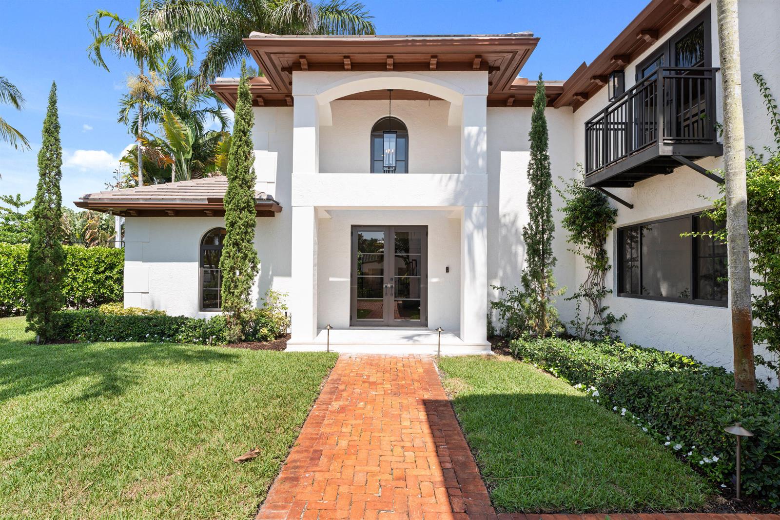A white two-story house features a brick walkway, a covered entryway, and a black balcony — 257 E Lakewood Road, West Palm Beach FL 33405, WEST PALM BEACH, FL
