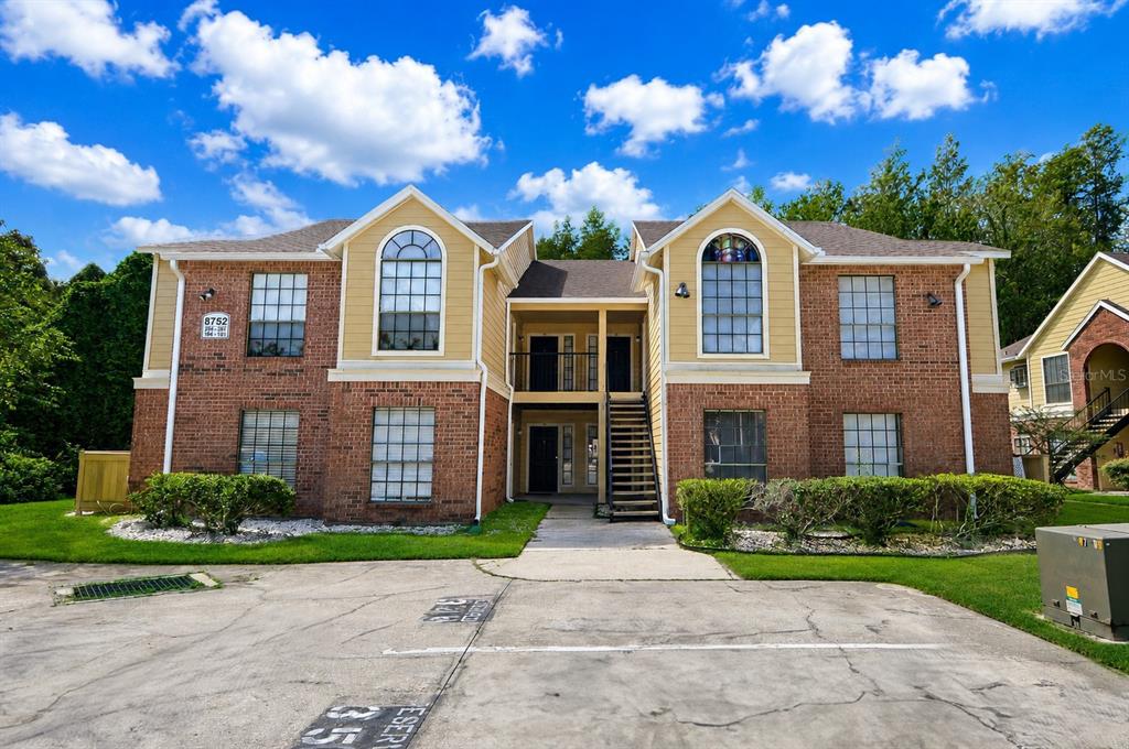 A two-story brick and tan apartment building with a central staircase and parking lot — 8752 MALLARD RESERVE DRIVE UNIT 203, TAMPA, FL