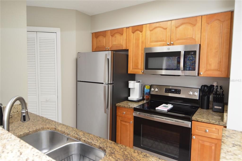 A kitchen features wood cabinets, granite countertops, and stainless steel appliances — 8752 MALLARD RESERVE DRIVE UNIT 203, TAMPA, FL