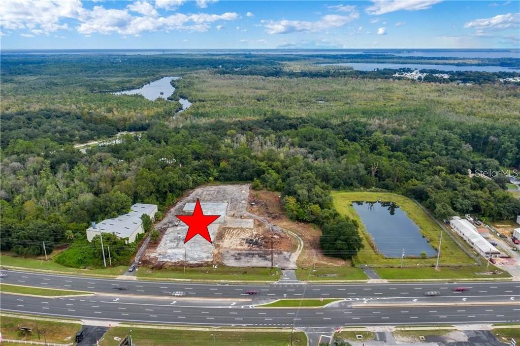 An aerial view shows a cleared, rectangular construction site with a concrete slab near a highway — 3131 US HIGHWAY 441 / 27, FRUITLAND PARK, FL