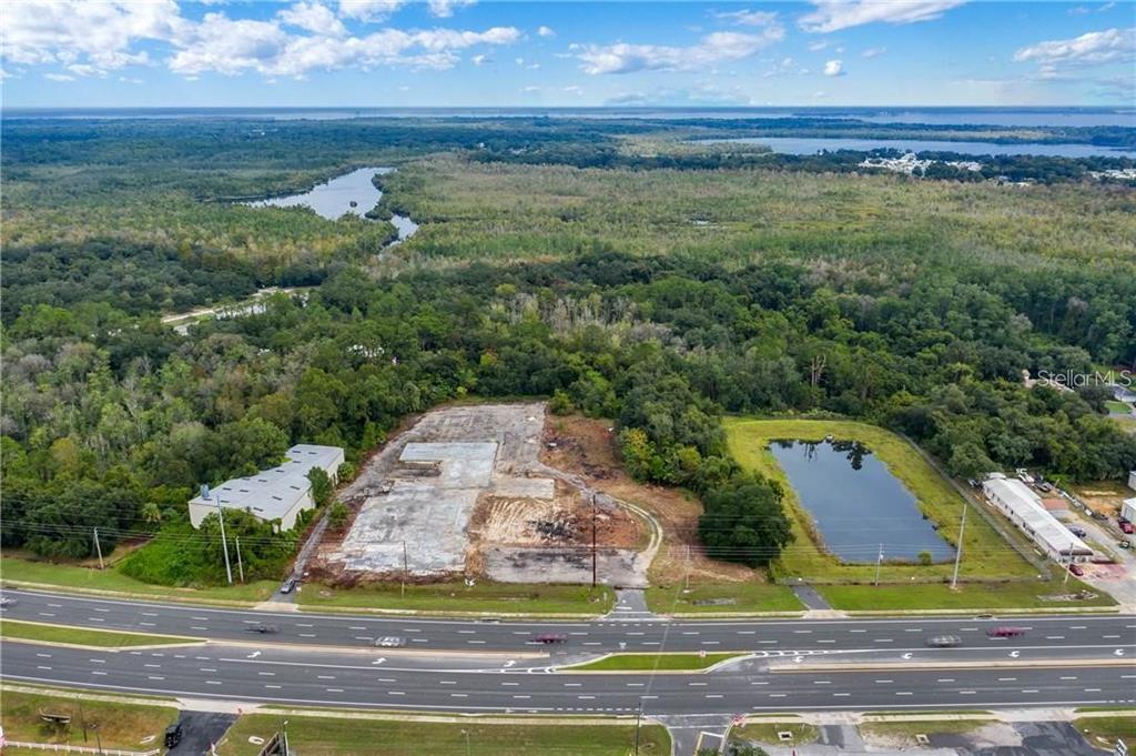An aerial view shows a cleared construction site with a concrete foundation next to a highway — 3131 US HIGHWAY 441 / 27, FRUITLAND PARK, FL