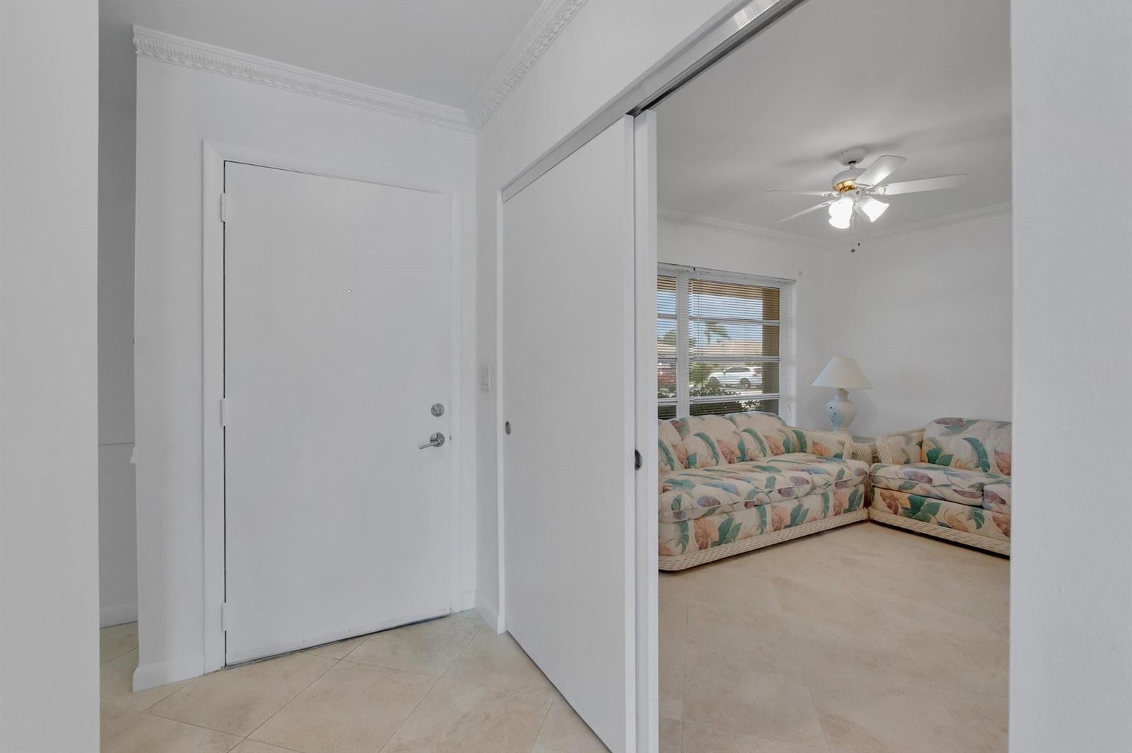 A white front door opens into a tiled entryway next to a living room area — 8829 Bella Vista Drive # 282, Boca Raton FL 33433, BOCA RATON, FL
