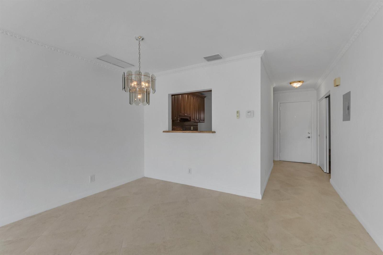 A dining area with a chandelier, tile flooring, and a pass-through window to the kitchen — 8829 Bella Vista Drive # 282, Boca Raton FL 33433, BOCA RATON, FL