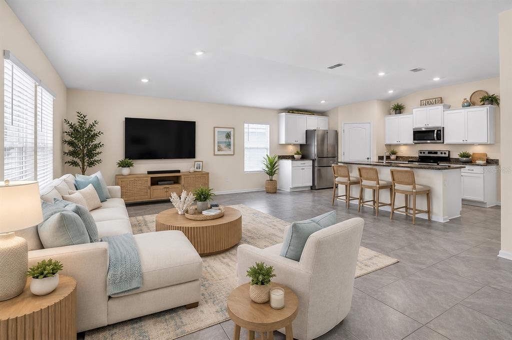 An open-concept living room and kitchen featuring light-colored furniture, tile flooring, and white cabinetry — 97 RIVERTOWN ROAD, PALM COAST, FL