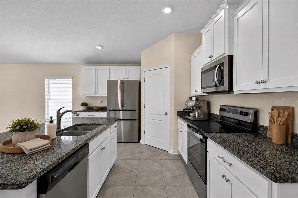 A kitchen features white cabinets, granite countertops, stainless steel appliances, and a central island — 97 RIVERTOWN ROAD, PALM COAST, FL
