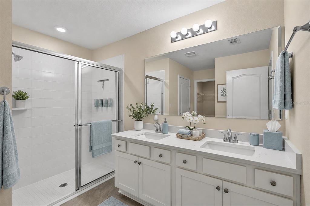 A bathroom features a double vanity with white cabinets, a large mirror, and a glass shower — 97 RIVERTOWN ROAD, PALM COAST, FL
