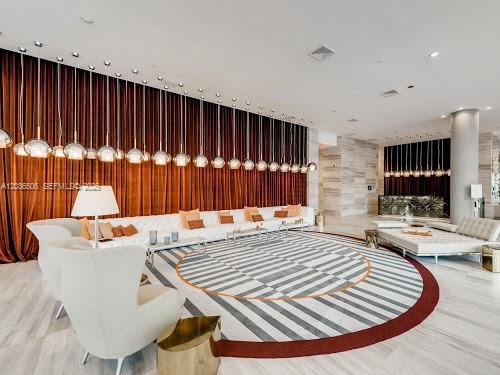 A modern lounge area features a long white sofa, armchairs, and numerous hanging pendant lights — 2000 Metropica Way # 2610, Sunrise FL 33323, SUNRISE, FL