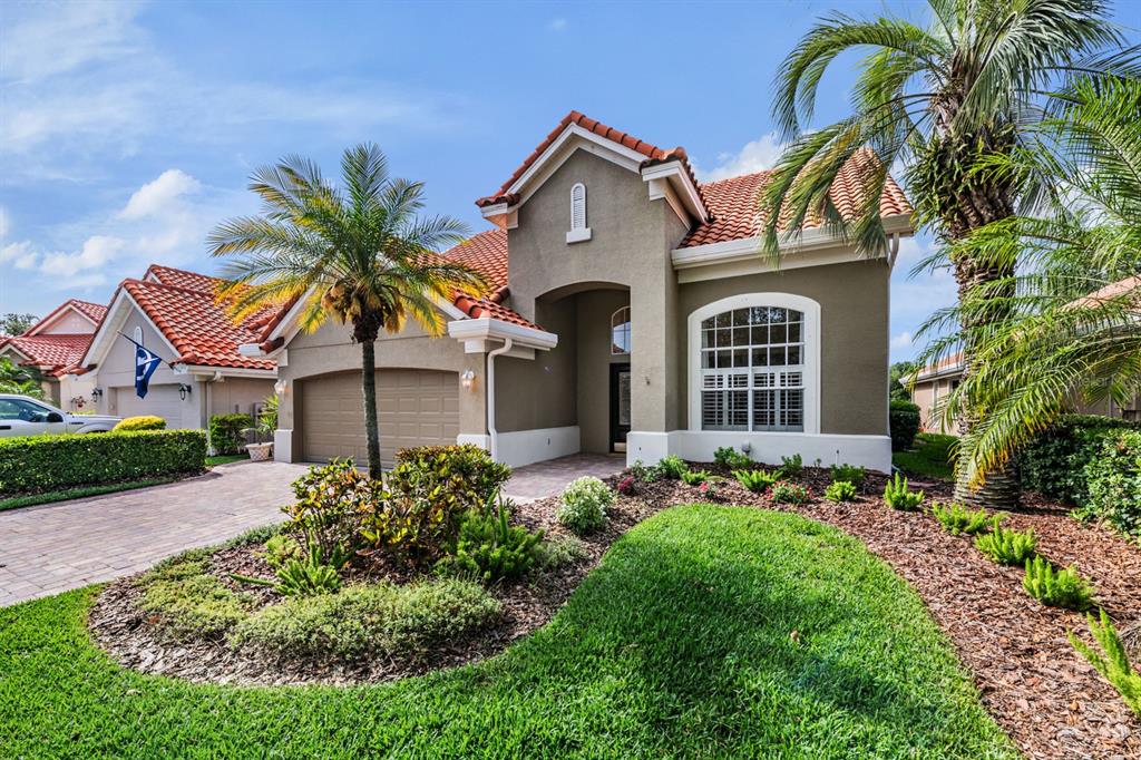 A single-story house with a tile roof, stucco exterior, and a landscaped front yard — 18911 AVENUE BIARRITZ, LUTZ, FL