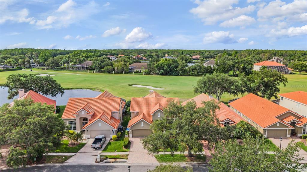 An aerial view shows a row of houses with orange tile roofs overlooking a golf course — 18911 AVENUE BIARRITZ, LUTZ, FL