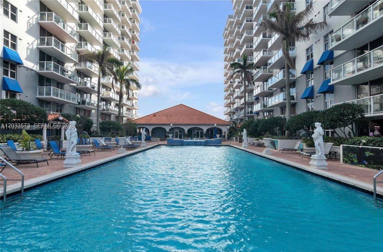 A long rectangular swimming pool sits between two tall residential buildings with balconies — 5091 NW 7th St # 906, Miami FL 33126, MIAMI, FL