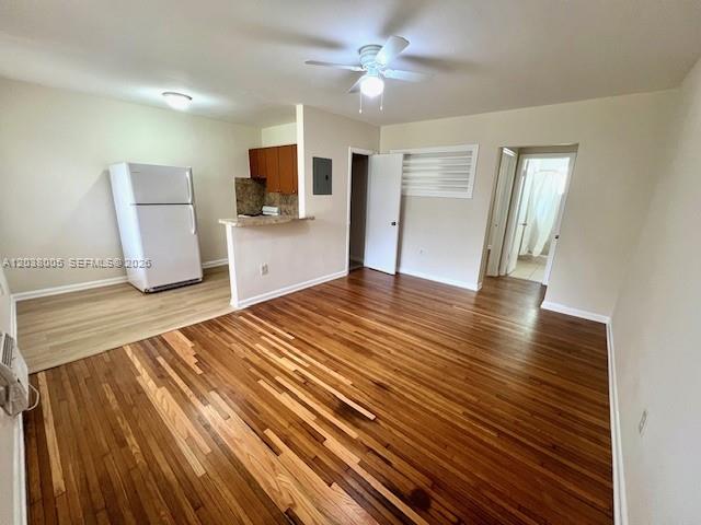 An open-concept room features hardwood floors, a white refrigerator, and a small kitchen area — 692 NE 85th St # 5, Miami FL 33138, MIAMI, FL