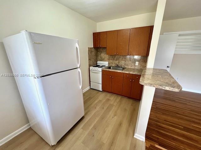 A kitchen features a white refrigerator, wood cabinets, a stove, and light-colored flooring — 692 NE 85th St # 5, Miami FL 33138, MIAMI, FL