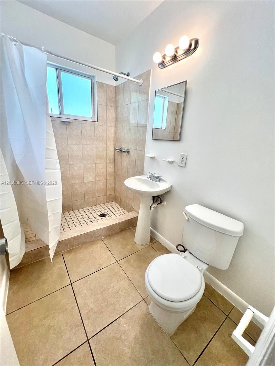 A bathroom features a tiled walk-in shower, a pedestal sink, and a white toilet — 692 NE 85th St # 5, Miami FL 33138, MIAMI, FL