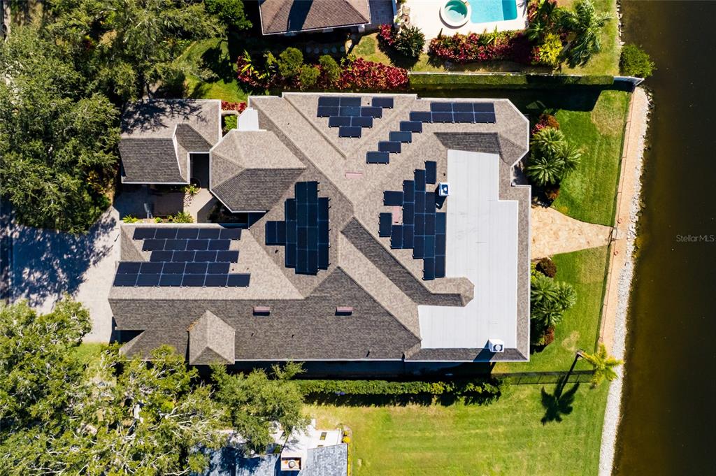 An aerial view shows a house with a shingled roof featuring multiple solar panel arrays — 8402 TALLAHASSEE DRIVE NE, ST PETERSBURG, FL