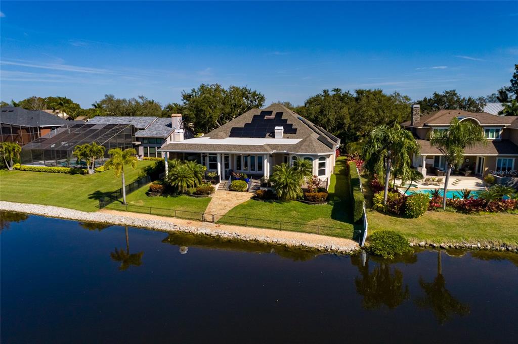 An aerial view of a waterfront house with solar panels on the roof and landscaping — 8402 TALLAHASSEE DRIVE NE, ST PETERSBURG, FL