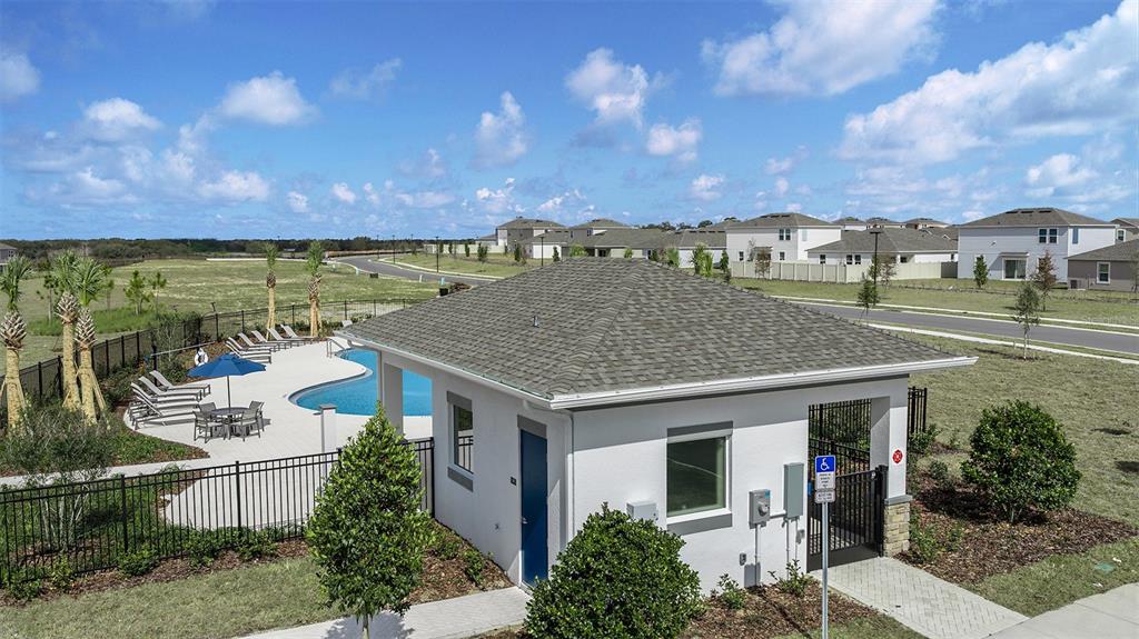 An exterior view of a community pool building with a gray roof and white walls — 515 MOONSTONE COURT, GROVELAND, FL