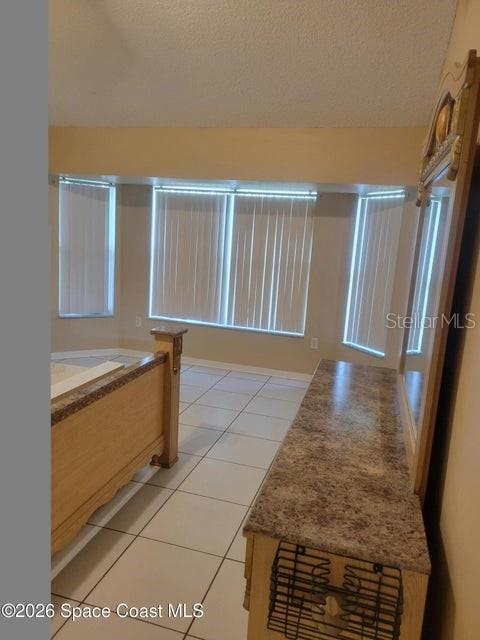 A bedroom features tile flooring, vertical blinds on large windows, and a wooden bed frame — 281 SEAHORSE CIRCLE SE, PALM BAY, FL