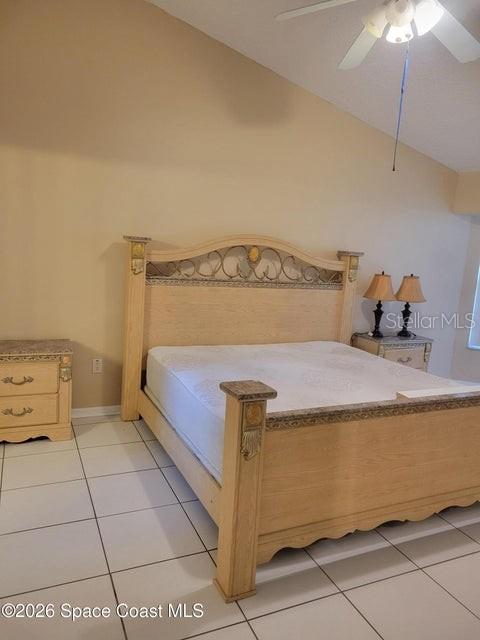 A bedroom features a light wood bed frame, matching nightstand, and white tile flooring — 281 SEAHORSE CIRCLE SE, PALM BAY, FL