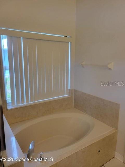 A bathroom features a built-in soaking tub with beige tile surround and vertical window blinds — 281 SEAHORSE CIRCLE SE, PALM BAY, FL