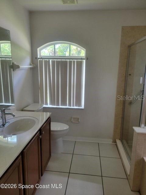 A bathroom features a vanity with a sink, a toilet, and a glass-enclosed shower — 281 SEAHORSE CIRCLE SE, PALM BAY, FL