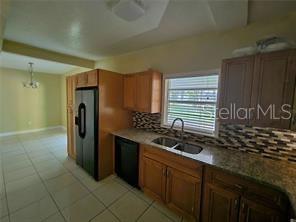 A kitchen features wooden cabinets, granite countertops, a tiled backsplash, and a black refrigerator — 4218 SEYBOLD AVENUE, ORLANDO, FL