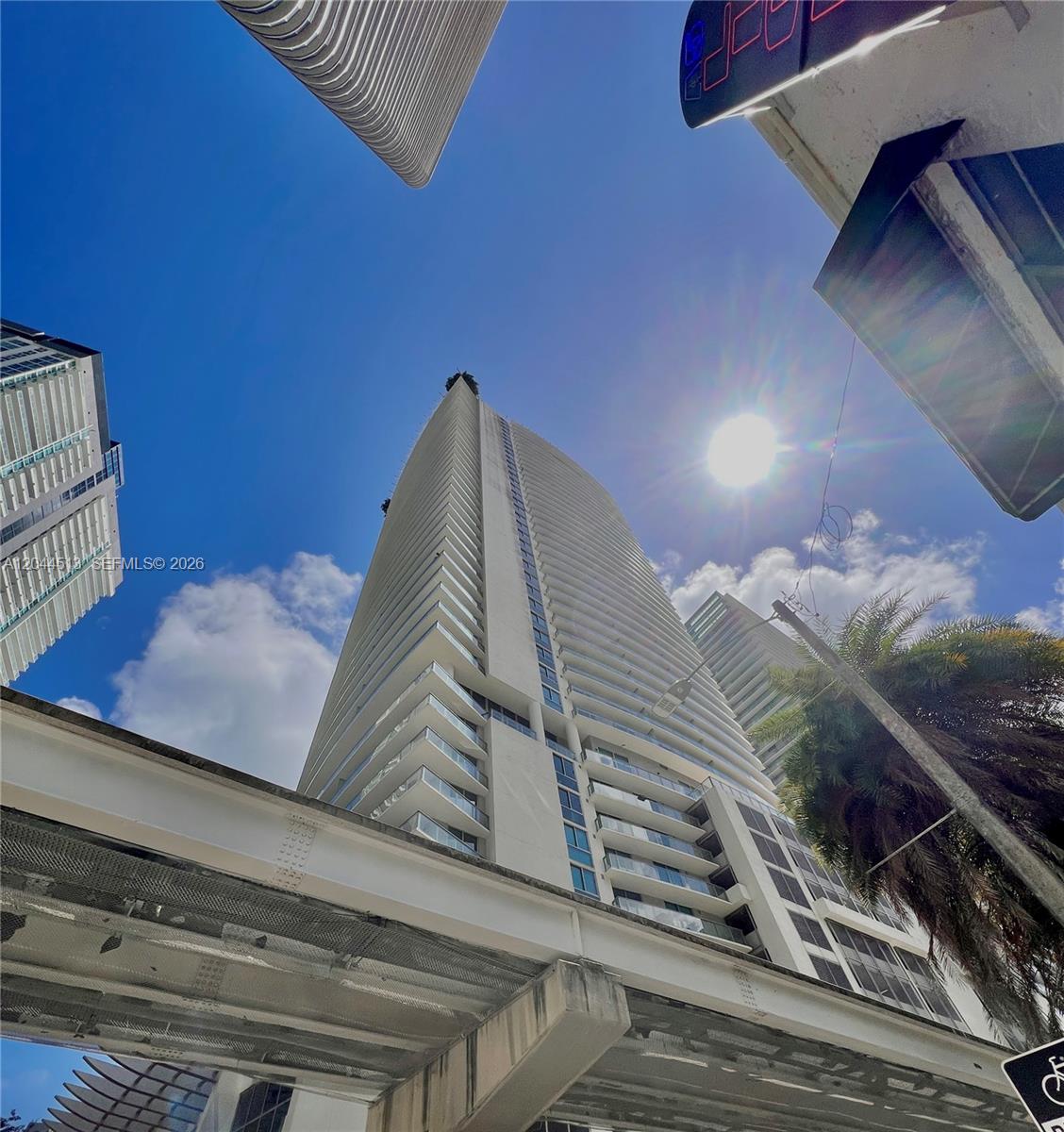 A low-angle view shows a tall residential skyscraper next to an elevated train track — 1100 S Miami Ave # 2002, Miami FL 33130, MIAMI, FL