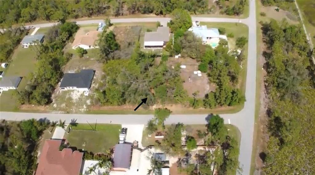 An aerial view shows a vacant, wooded residential lot situated between existing houses and streets — 23332 AIRWAY AVENUE, PORT CHARLOTTE, FL