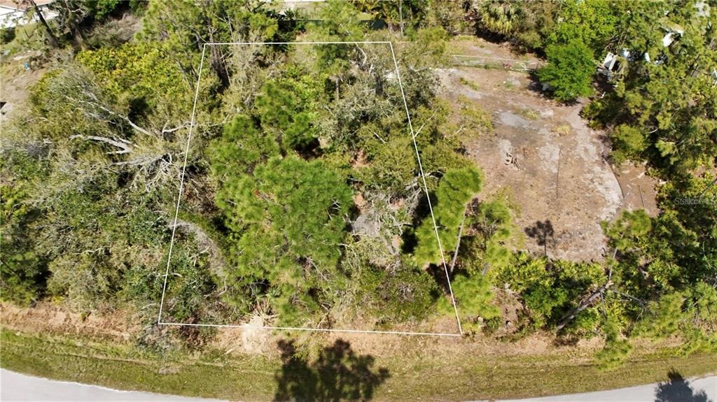 An aerial view shows a wooded, trapezoidal plot of land bordering a paved road — 23332 AIRWAY AVENUE, PORT CHARLOTTE, FL