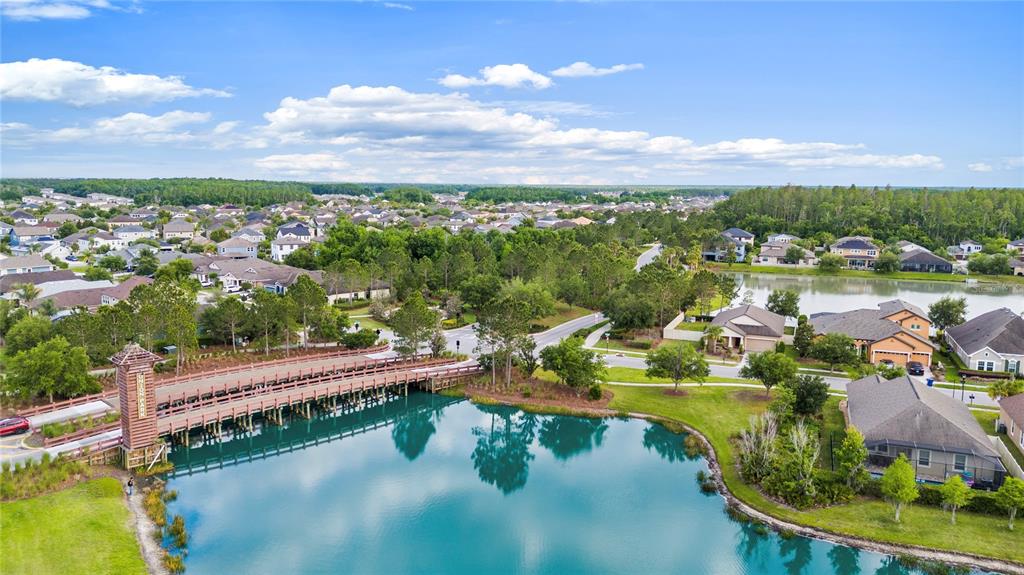 An aerial view shows a wooden bridge crossing a pond in a residential neighborhood — 31976 WATOGA LOOP, WESLEY CHAPEL, FL